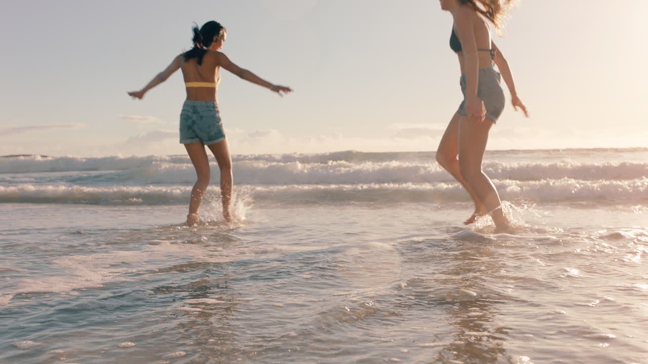 해변에 있는 여자 친구 들 이 서로 바 ⁇ 물 을  ⁇ 아 즐기고 따뜻 한 여름 날 바 ⁇ 가 에서 게임 을 하고 여름 휴가 를 즐기고 있다