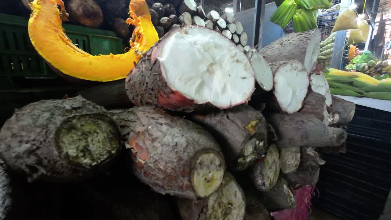 Zooming out from cut yuca and auyama roots on display in Caracas indoor market.
