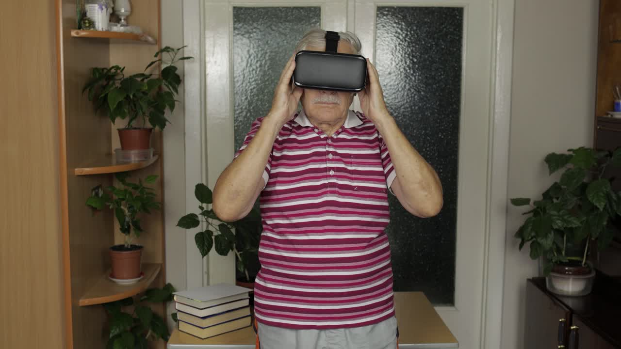 Senior grandfather putting on virtual headset glasses and watching 3d video in 360 vr helmet at home