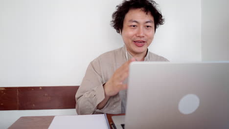 adult man sit and take note for online studying with laptop in cafe during daytime