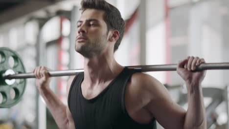 sportsman training squat exercise with barbell in fitness club.