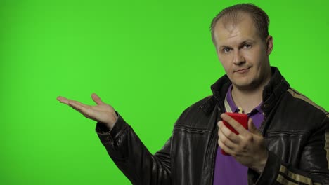 rocker man showing side advertising area. using smartphone, pointing at wall for your text, logo