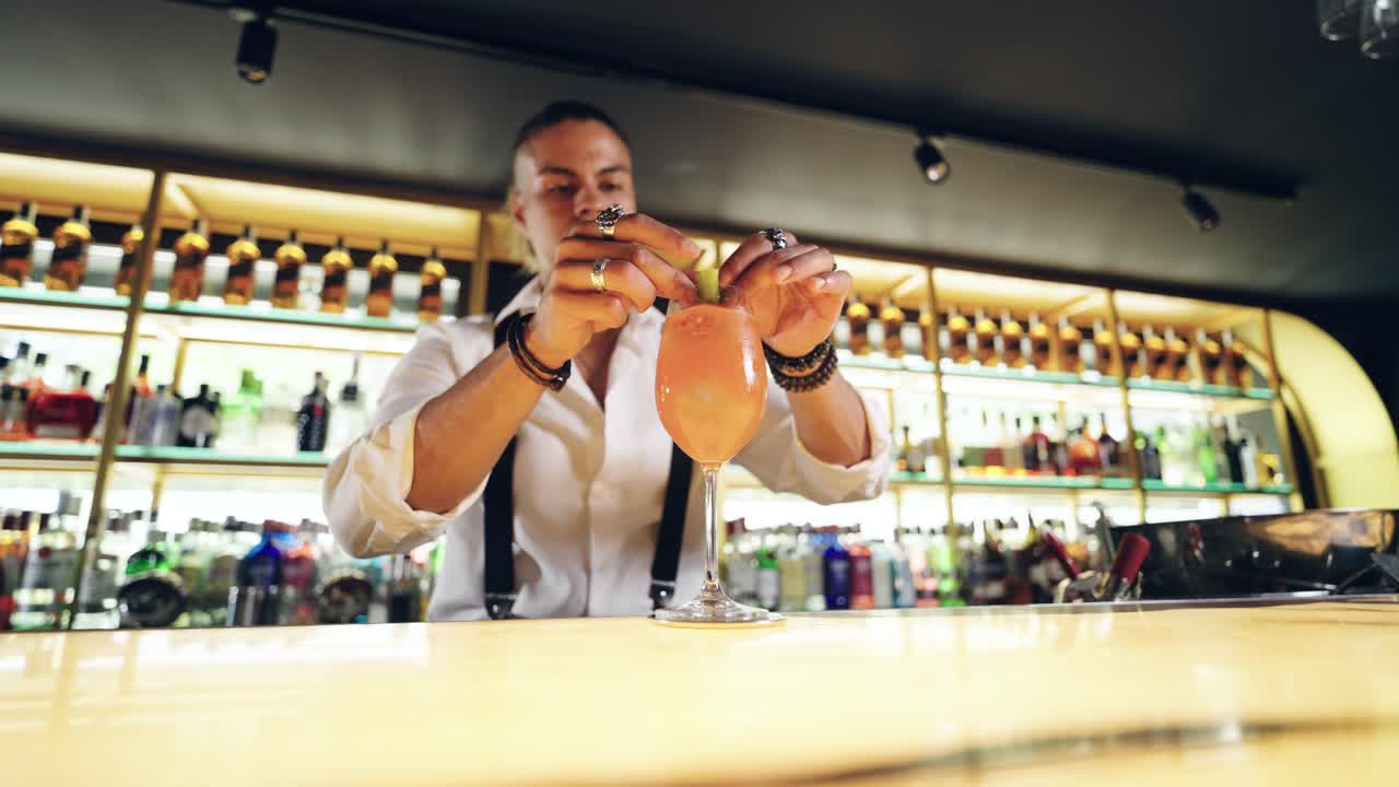 Professionel bartender pynter dygtigt en orange cocktail med limeskal