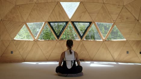 woman sitting cross legged, centered, a calming yoga session in a zen geometric studio, focusing on mindfulness with a hispanic woman