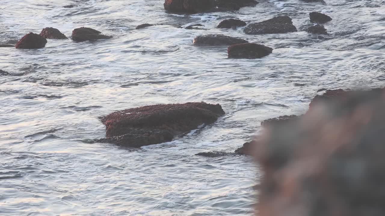 일출 때 바위와 바다의 흐릿하고 집중된 움직임은 혼합된 색상과 질감이 조화롭게 움직이는 매혹적인 장면을 만듭니다.