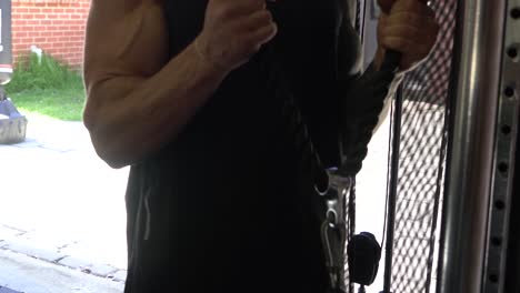 muscly man in home gym exercising cable bicep curl