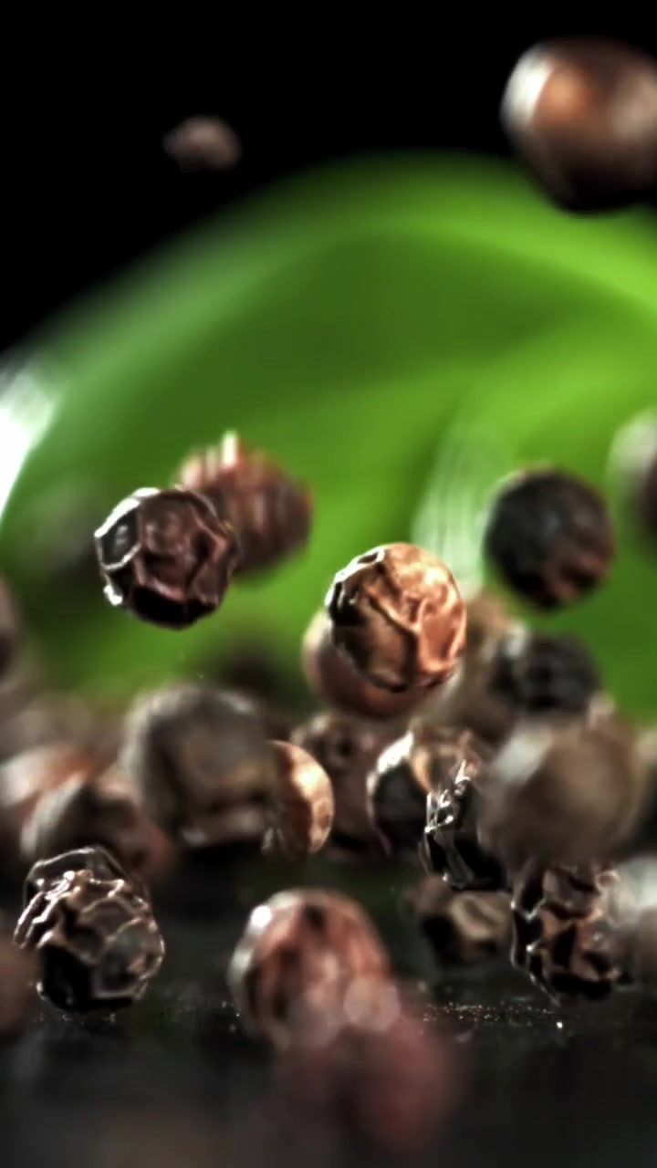 Grani di pepe nero interi che cadono in super slow motion