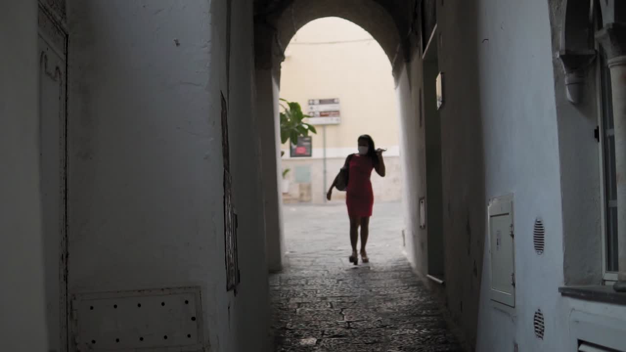 одинокая женщина с маской на лице идет по улицам и проезду в городе амальфи италия