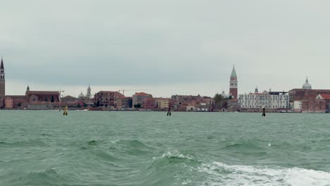 boat ride in venice lagoon with cityscape in distance on cloudy day, slow motion