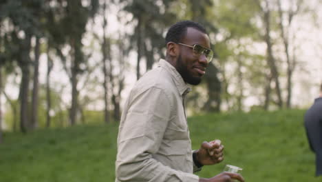 Close-Up-View-Of-An-Middle-Aged-Man-Dancing-While-Drinking-Wine-In-The-Park