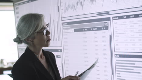 professional businesswoman in suit standing in front of big screen