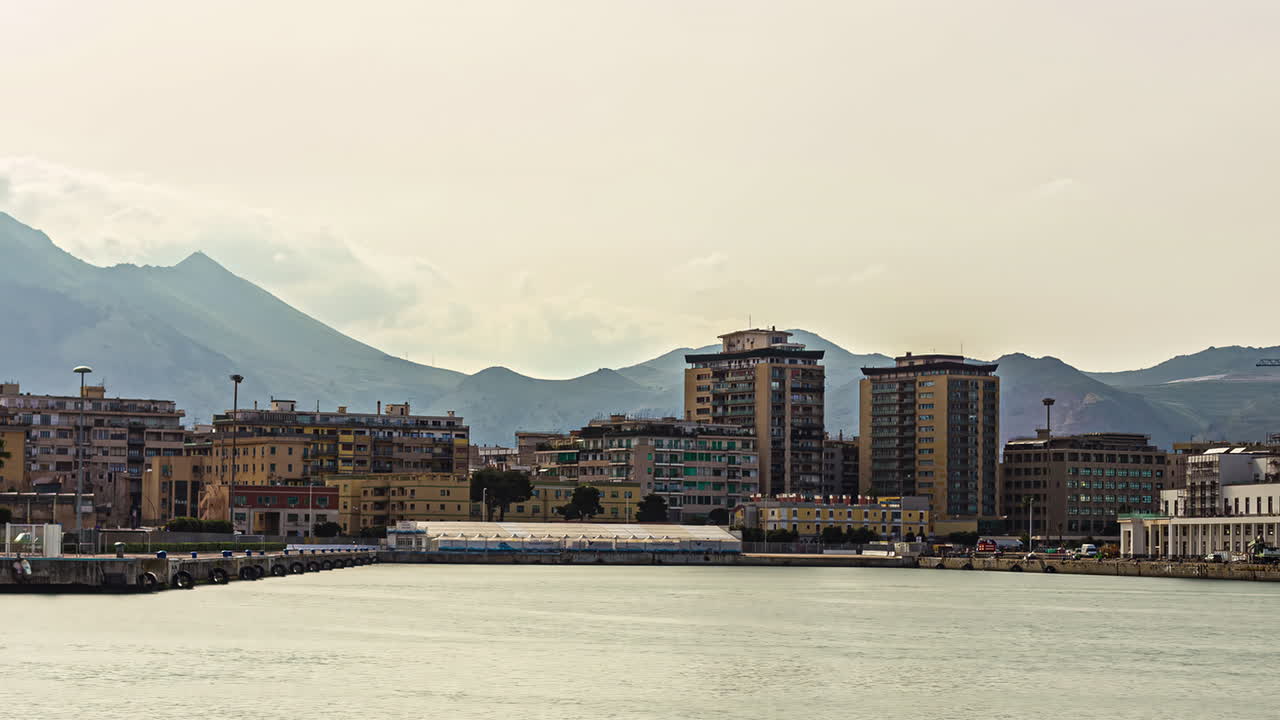 이탈리아의 아름다운 도시 시칠리아의 해안 앞에서 시끄러운 바다를 바라보며 움직이는 카누 보트, 역사적인 건물과 저녁에 배경에 있는 산을 바라보는 타임 스