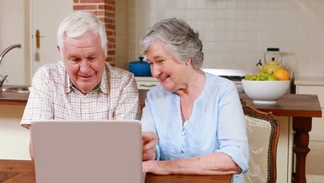 una pareja mayor usando una computadora portátil juntos.