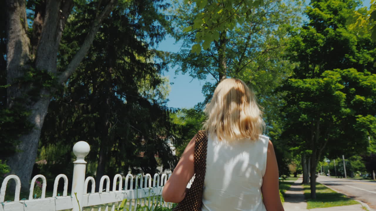 전형적인 미국 교외의 뒷모습으로 길을 걷고 있는 젊은 여성