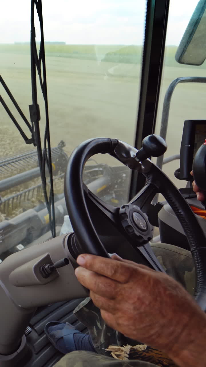 Man working in field in grain combine. View on process of gathering wheat from inside cabin Vertical video
