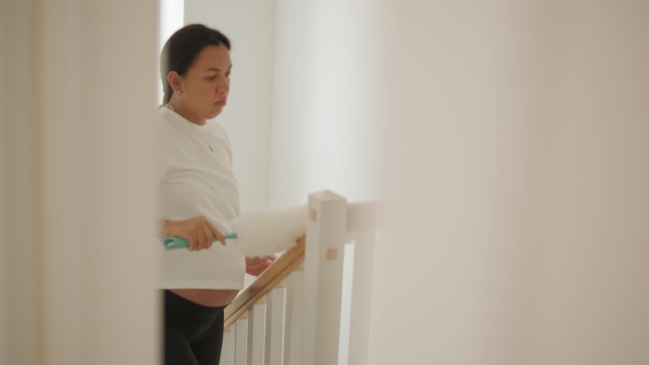 una hermosa mujer embarazada ordenando su casa, ocupada en las tareas domésticas. la escena captura la vida doméstica, la maternidad y el equilibrio de la rutina y la preparación durante el embarazo
