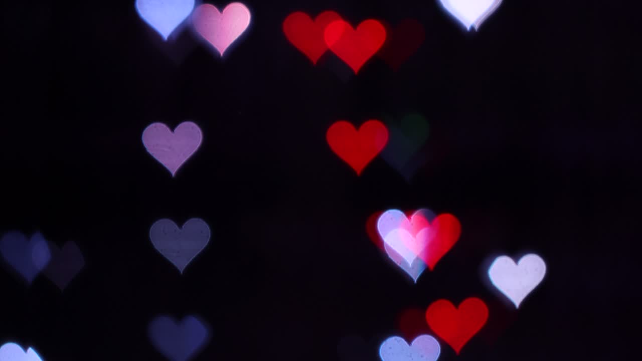 4k uhd video de fondo para el día de san valentín. frontera con bokeh de corazones románticos brillantes y relucientes en un fondo negro. amor, bokeh en forma de corazón.