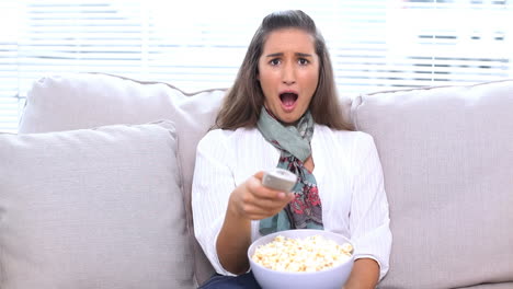 brunette watching television and eating popcorn