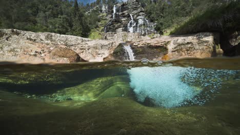 una tranquila escena fluvial con orillas rocosas, agua cristalina y una pintoresca cascada