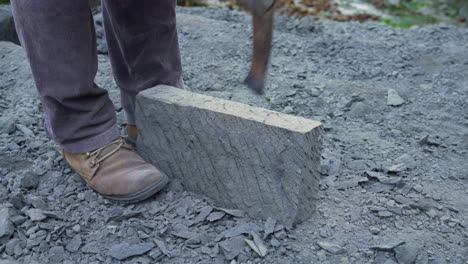 Handheld-shot-of-a-craftsman-using-a-pick-to-shape-a-slab-of-cancagua-stone-in-the-city-of-Ancud-on-Chiloe-Island