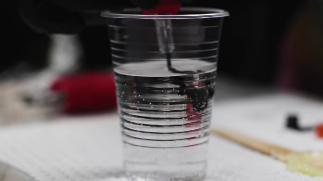 Ago che dissolve l'inchiostro nell'acqua durante il tatuaggio.