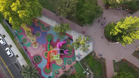 Aerial-overhead-shot-of-playing-children-on-colorful-playground-in-Buenos-Aires-City---slow-motion-orbit-shot
