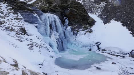 Waterfall,-Helgufoss,-covered-in-snow-and-ice-in-early-Spring