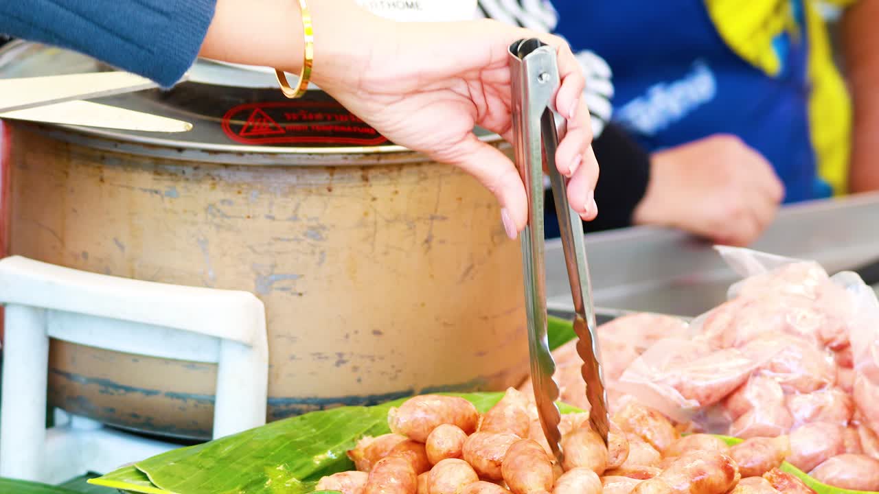 길거리 음식 판매자 가 그릴 소시지를 준비 하고 있다