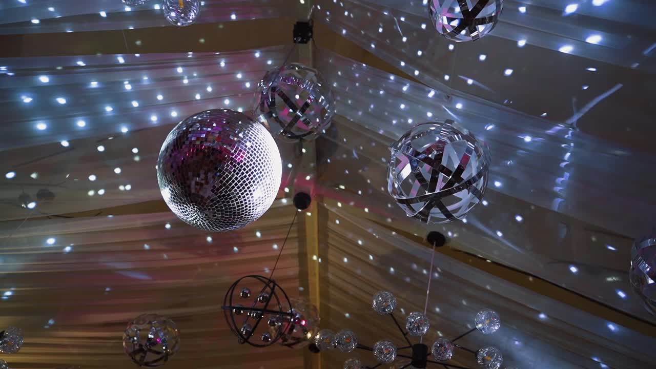 Tavanda yuvarlak disko topu ve çeşitli boyutlarda lambalar. Konser salonunda canlı bir şekilde yanıp sönen parlak ışıklar.