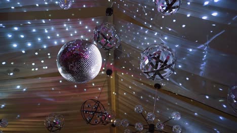 Round disco ball and many sized lamps on the ceiling. Sparkling lights flashing brightly in the concert hall.