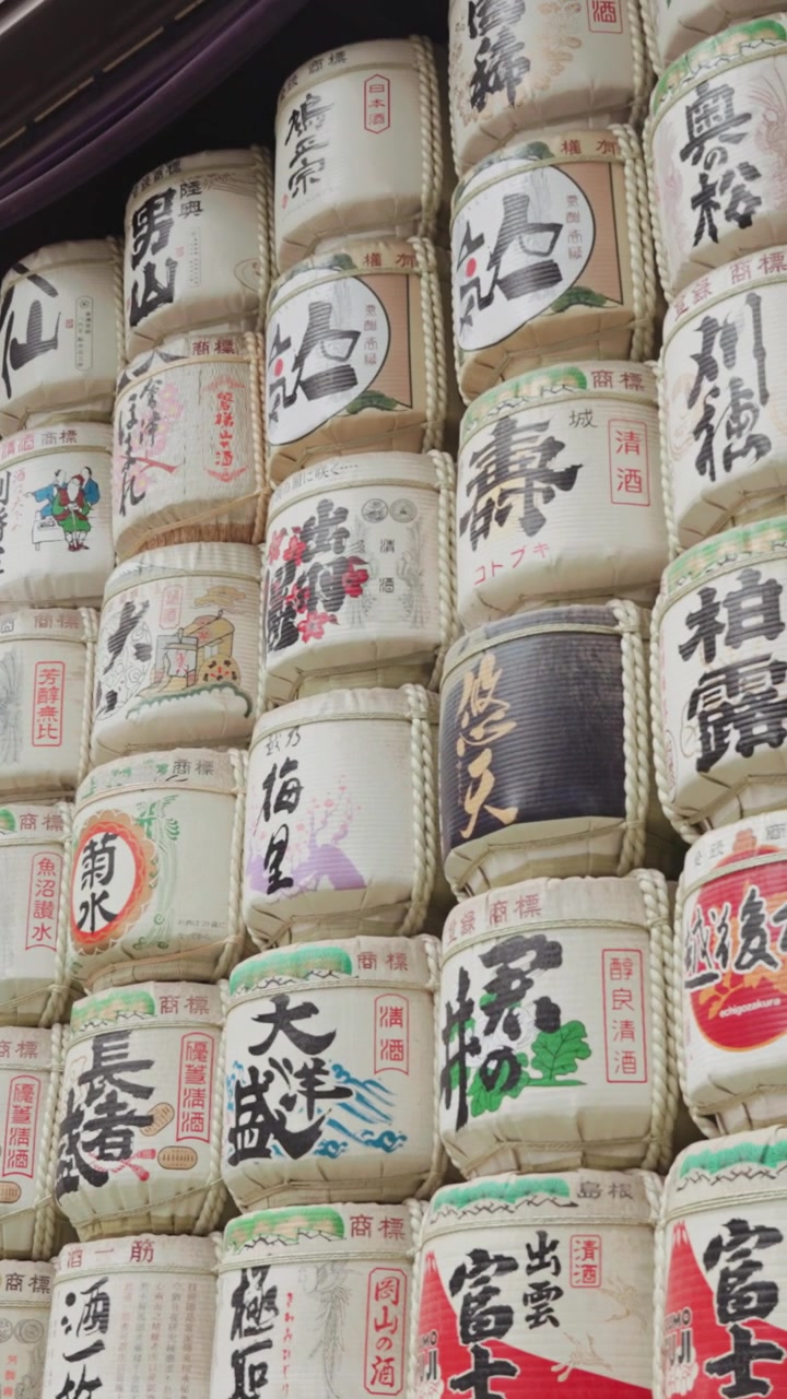 Vertical slow-motion panning along colorful sake barrels at Meiji Jingu Shrine during the daytime in Yoyogi Park in Tokyo.