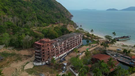 abandoned rusty ghost ship on koh chang on tropics island bay, thailand, during sunset, with a crane working on it. nice aerial view flight drone camera pointing down
