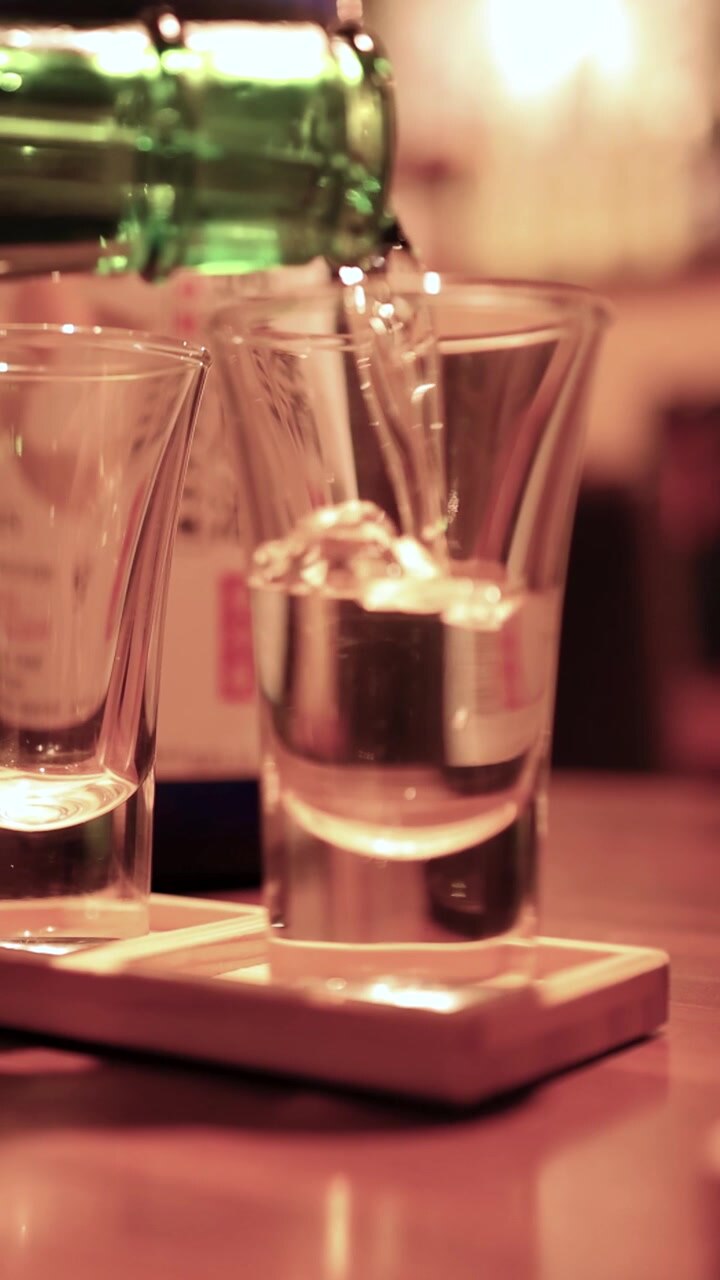 Primo piano di sake trasparente versato in bicchieri su un vassoio di legno a Tokyo
