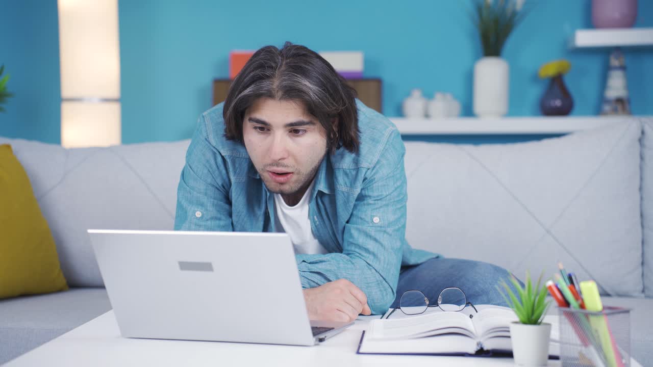 joven mirando la computadora portátil con atención.
