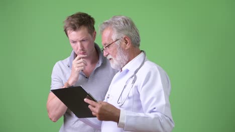 anciano barbudo médico consultando hombre paciente contra fondo verde