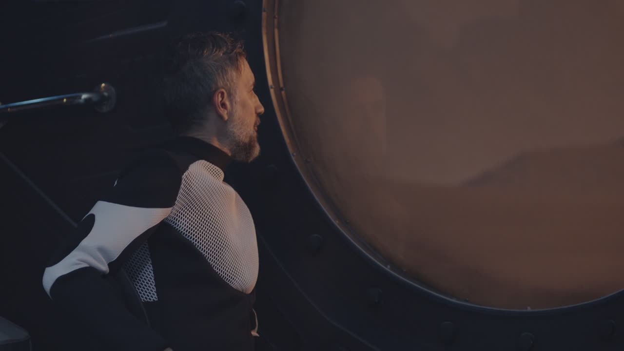 Man in Fashionable Outfit Leaning Against a Large Window