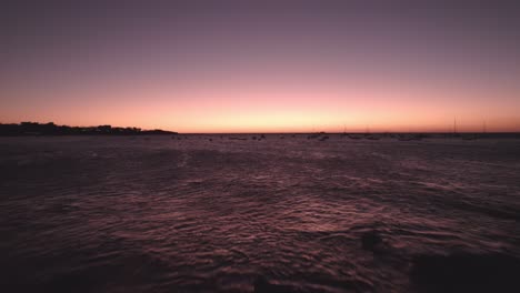 beautiful pink sky sunset on horizon and woman with arms up on rocky beach shore, 4k tamarindo beach costa rica drone