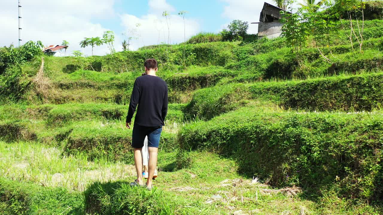 Bali, Ubud, Indonesia, Young lovely couple walking on the terraced rice fields. Siblings enjoying pristine nature and rural landscape