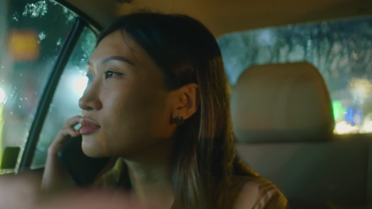 Asian Woman Chatting on Phone and Riding in Taxi at Night