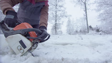 motosierra cu - una mujer corta un agujero de hielo para la terapia de exposición al agua fría