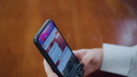 vista parcial de alguien hablando por teléfono en la mesa, participando en una conversación, con un claro enfoque en la mano y el teléfono mientras que un fondo borroso da un entorno personal e íntimo