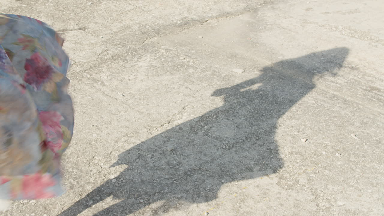 High quality video of a long shadow moving across a sunlit Havana street, capturing rough pavement textures and warm Caribbean light