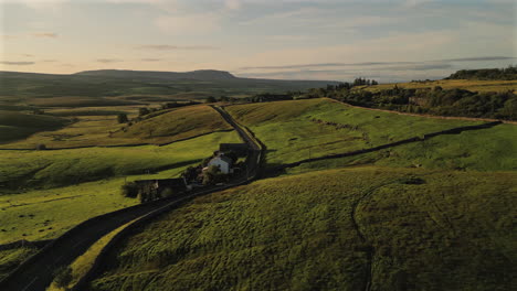 establishing drone shot of fields and hills and farmhouse at golden hour