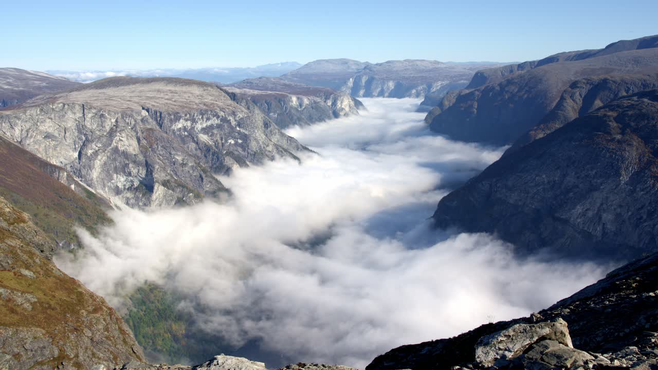 A timelapse from Bakkanosi mountain showing clouds clearing over Nærøyfjord, revealing the fjord below, with a slow push- n movement