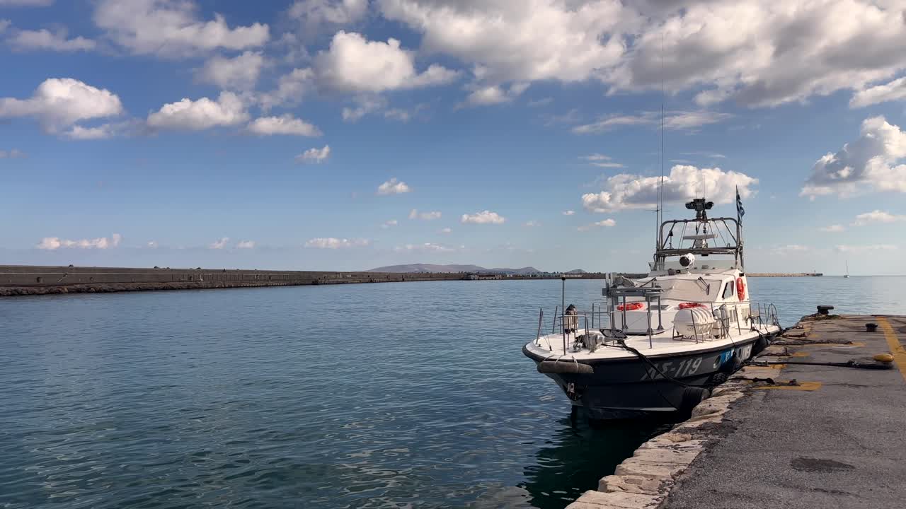 Boat docked at Heraklion port with calm waters and clouds, Crete, Greece