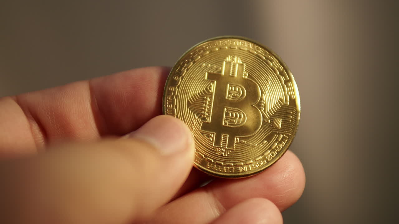 detalle de la mano que sostiene la moneda de oro bitcoin