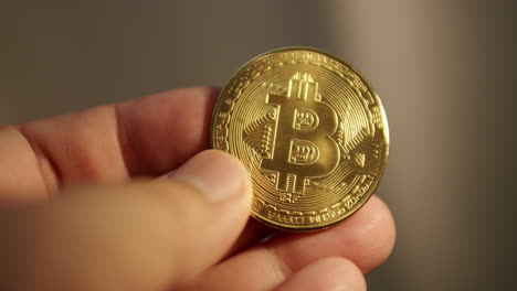 detail of hand holding gold bitcoin coin