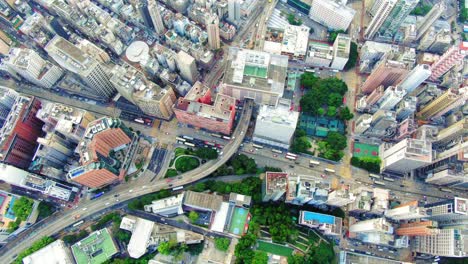 Traffic-passing-through-a-Car-park-building-in-downtown-Hong-Kong,-with-city-mega-buildings,-Aerial-view