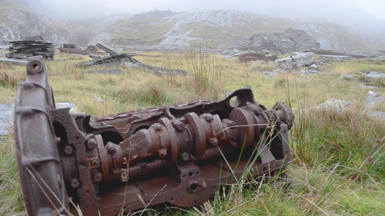 una pieza oxidada de maquinaria retirada que se encuentra en la ladera de una montaña galesa sobre una cantera cerca del pueblo minero abandonado de la cantera de pizarra cwmorthin en las montañas moelwyn cerca de tanygrisiau, gales del norte