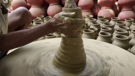 potter making clay vessel with hands.